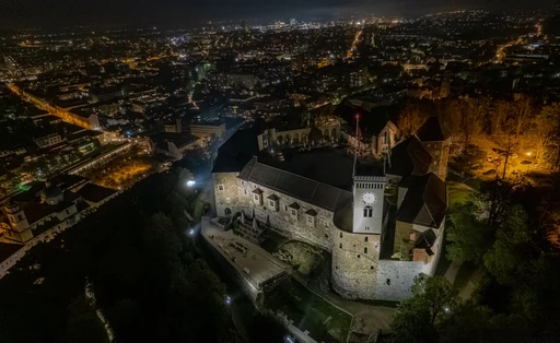 Stunning aerial view of Ljubljana Castle illuminated at night over the city skyline.