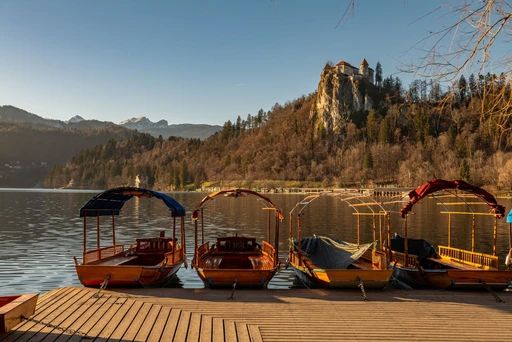 Scenic view of Lake Bled and castle with four pletna boats in Slovenia.