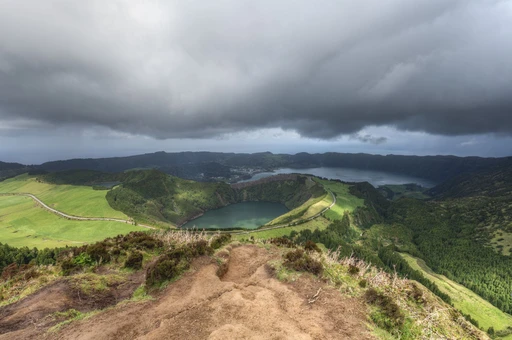 Scenic aerial view of Sete Cidades crater lake in the Azores under dramatic cloudy skies.