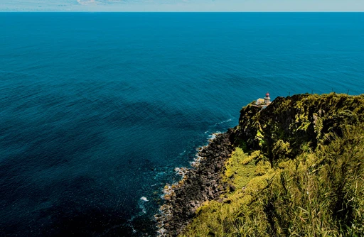 A captivating aerial view of the coastal cliffs and lighthouse in Nordeste, Azores, Portugal.