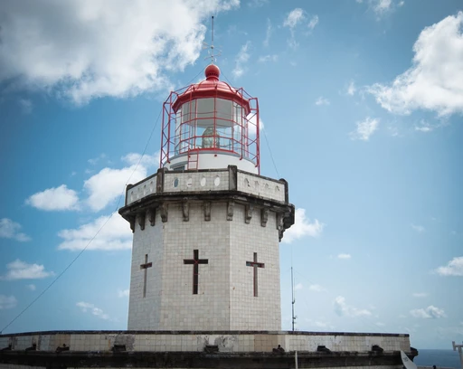 Iconic lighthouse standing tall under a blue sky at the Azores, Portugal.