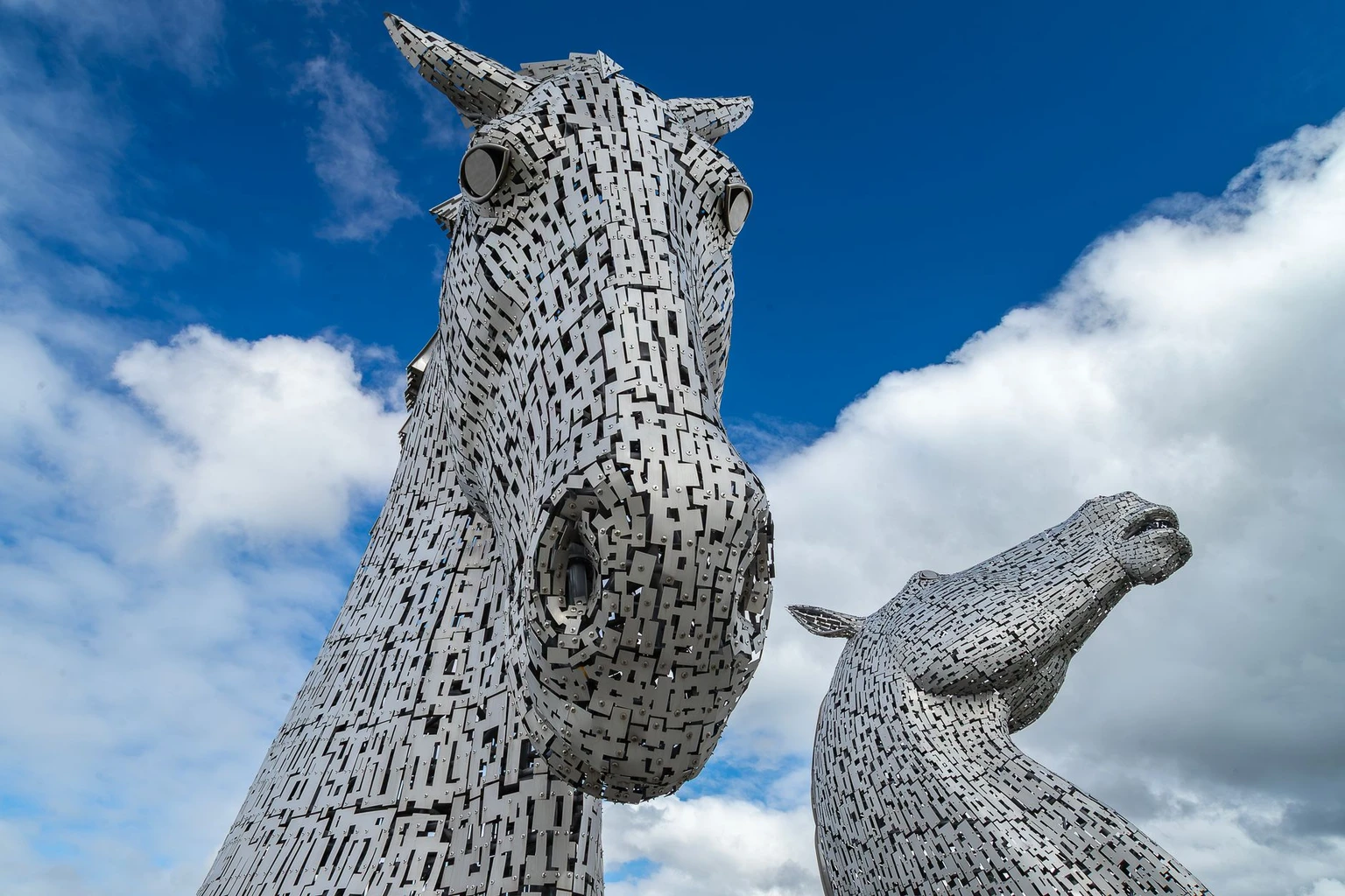 Stunning close-up of The Kelpies sculptures in Grangemouth, Scotland, under a bright blue sky.