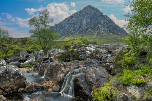 Scenic view of Buachaille Etive Mòr with a rocky stream in the Scottish Highlands during summer.