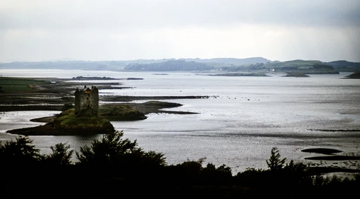 Majestic view of Castle Stalker nestled on islet in Scotland with serene waters surrounding.