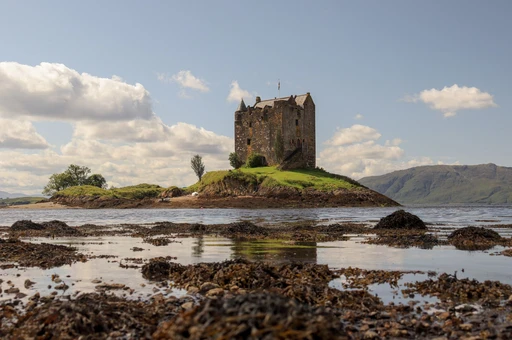 Scenic view of Castle Stalker on Loch Linnhe with cloudy sky in Scotland.