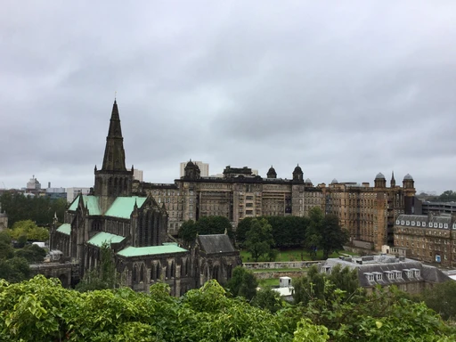 Glasgow Cathedral and the city seen from the high ground of the Necropolis on an overcast day.