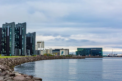 Reykjavík's waterfront with modern glass buildings and the Harpa concert hall across the water.