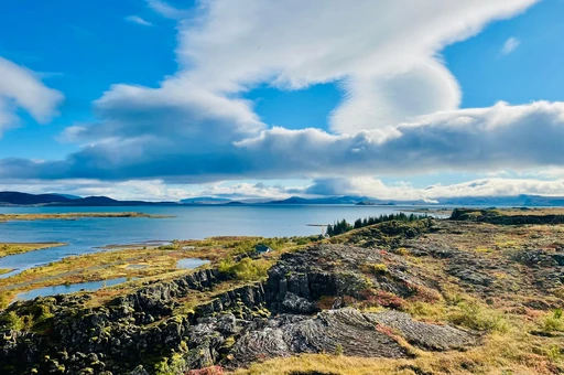 Stunning landscape view of Þingvellir National Park showcasing cliffs and lake under a blue sky.