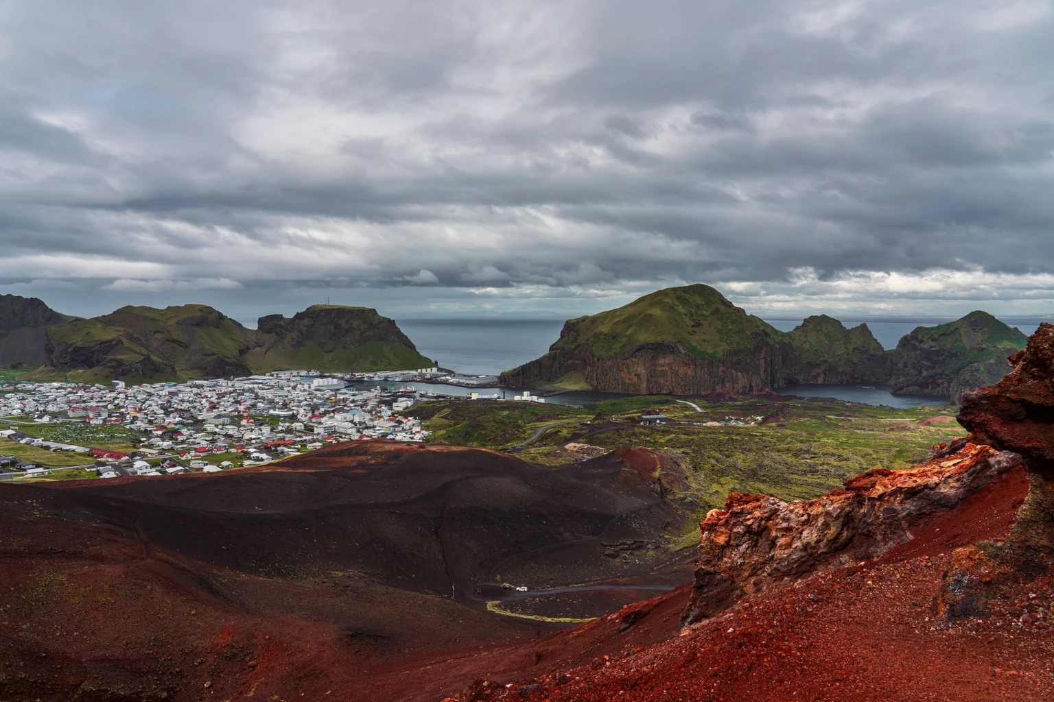 A stunning aerial view of Heimaey Island in Iceland featuring volcanic landscapes and a coastal town.