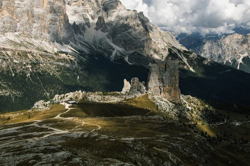 The Cinque Torri rock group seen from above, lit in patches by sun under heavy cloud.