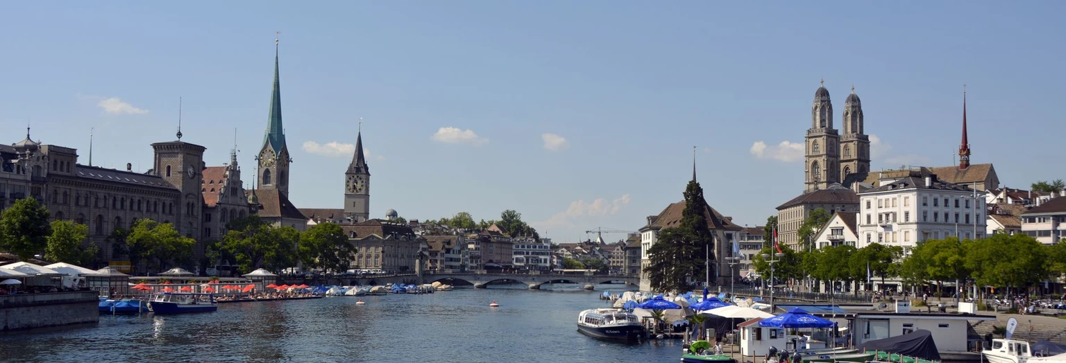 Explore Zurich's historic cityscape along the waterfront with iconic churches and bustling activity.