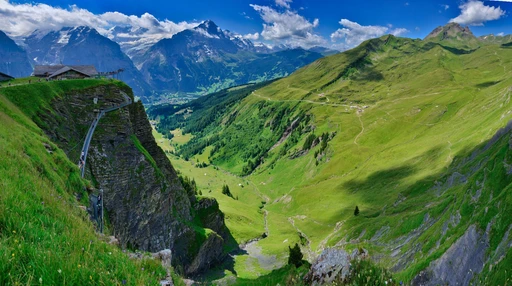 The First Cliff Walk, a steel walkway bolted to the rock face above the Grindelwald valley, with snow-capped peaks beyond.