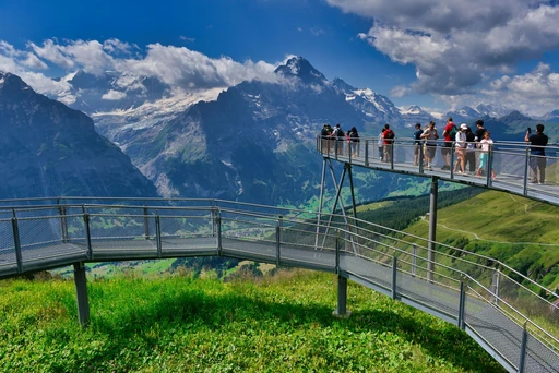 Visitors on the First Cliff Walk platform above Grindelwald, with glaciated peaks behind.