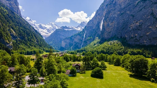 Breathtaking aerial view of the lush green Lauterbrunnen Valley amidst towering mountains and waterfalls.