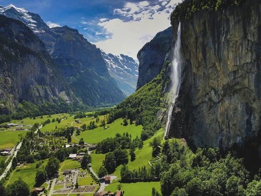 Scenic view of Lauterbrunnen Valley in Switzerland, featuring a majestic waterfall and lush green landscape.