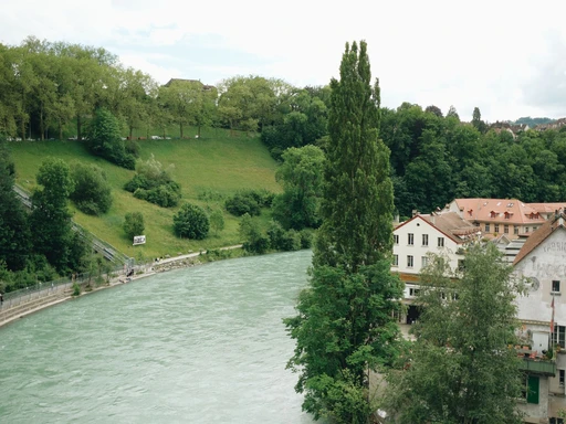 The turquoise Aare river running past green banks and old houses in Bern.
