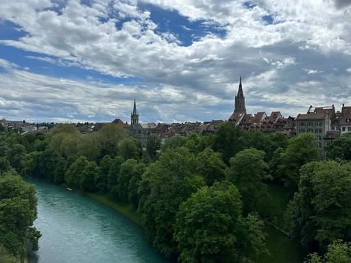 Panoramic view of Bern's old town with Aare River and iconic spire, rich in history.