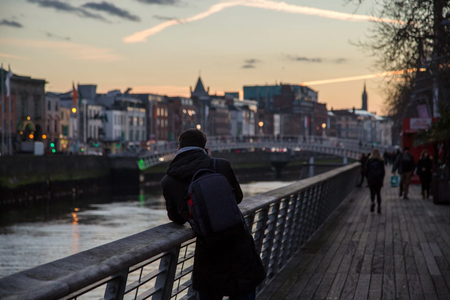 Silhouette of a person enjoying the sunset view of Ha'penny Bridge in Dublin, Ireland.