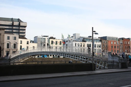 Iconic Ha'penny Bridge over River Liffey with city backdrop, Dublin, Ireland.