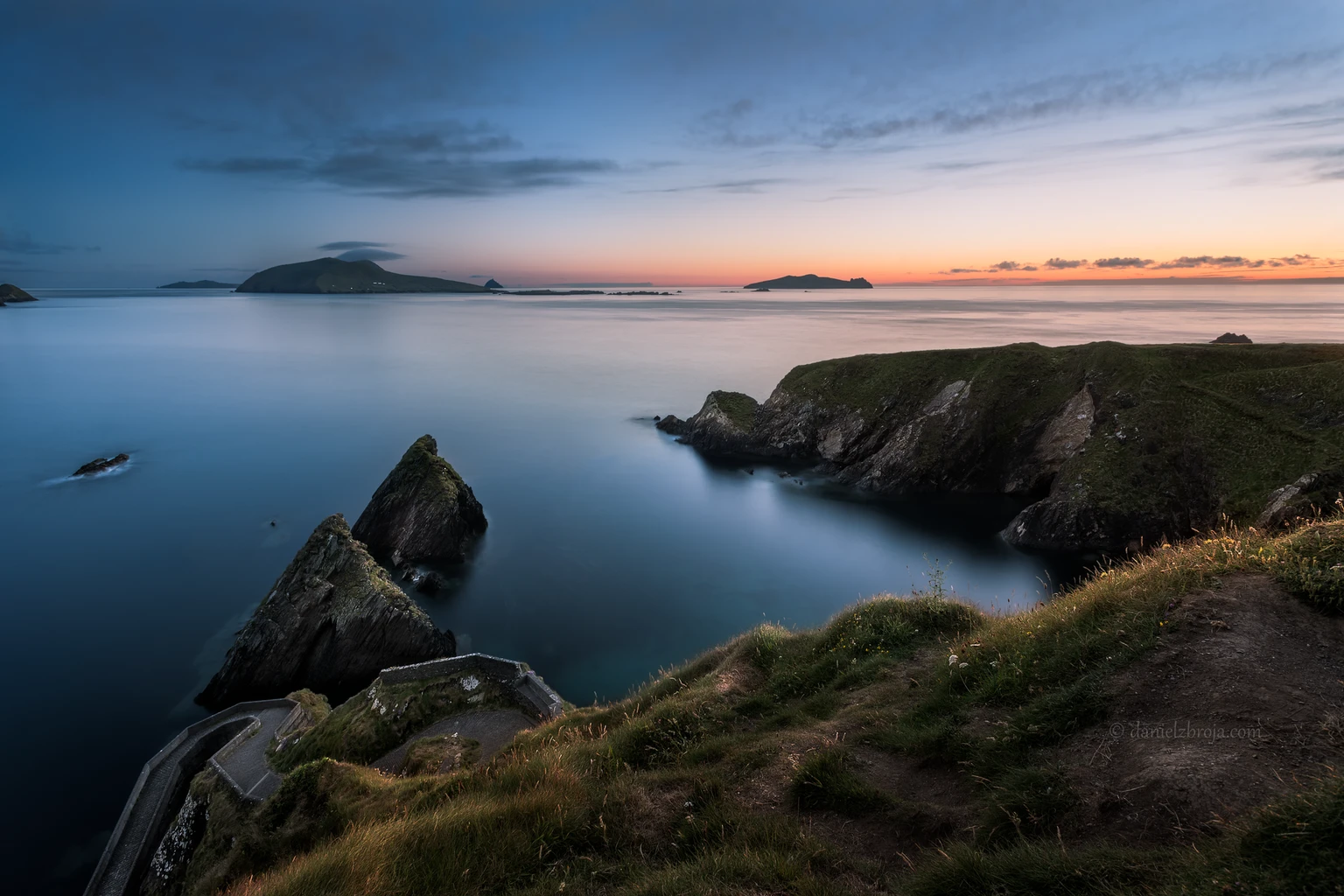 Stunning view of Dunquin Pier at sunset with serene waters and dramatic cliffs in County Kerry.