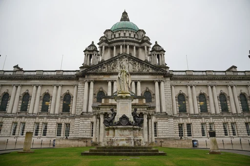 The front of Belfast City Hall, its green dome above the Edwardian facade and the statue in the grounds.