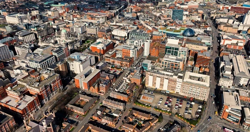 Aerial view over the centre of Belfast, brick and stone buildings packed along the city streets.