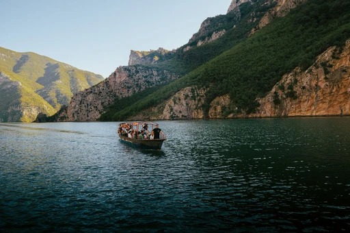 Explore the serene beauty of Koman Lake with a scenic boat ride amidst Albania's majestic mountains.