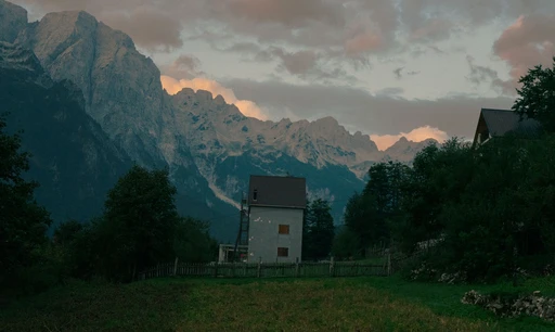 Scenic landscape of Valbonë, Albania with dramatic mountain range and quaint home at dusk.