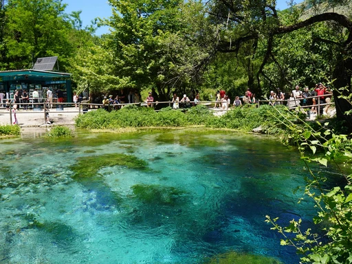 People enjoy the natural beauty of the Blue Eye spring, surrounded by lush greenery in Albania.