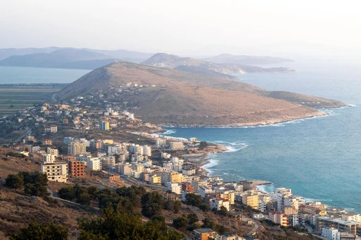 Explore the picturesque coastal view of Sarandë, featuring Lekursi Castle in the enchanting evening light.
