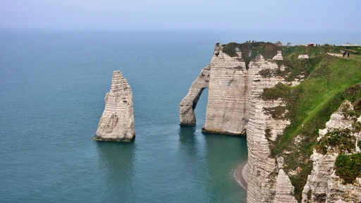 Étretat's needle and cliff arch from above in soft evening light, the sea calm below.