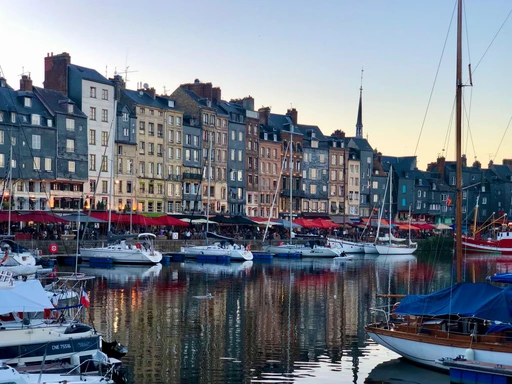 Honfleur's harbor at sunset, with colorful houses and moored boats.
