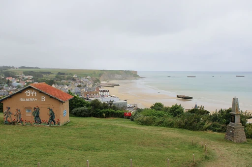 The beach at Arromanches-les-Bains on an overcast day, with the remains of the Mulberry harbor in the sea.