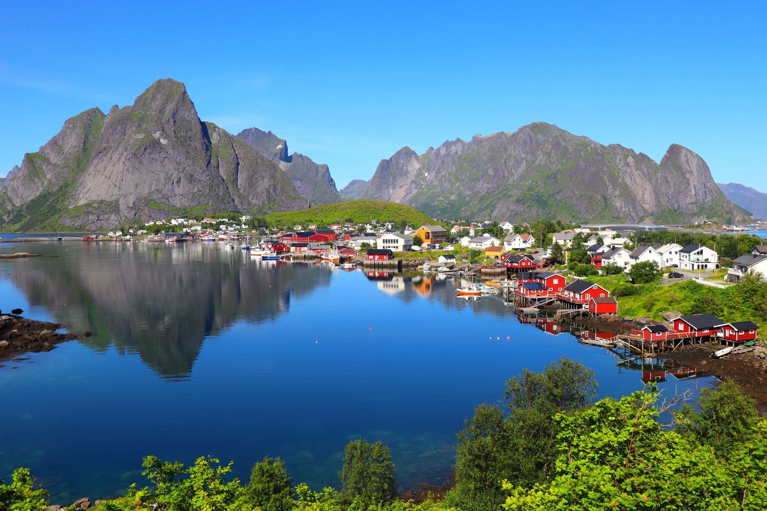 Reine village and its mountains reflected in still water, Lofoten, in summer.