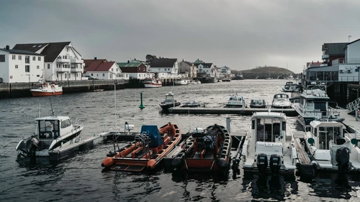 Boats and white buildings in Henningsvær harbor under a cloudy sky, Lofoten.