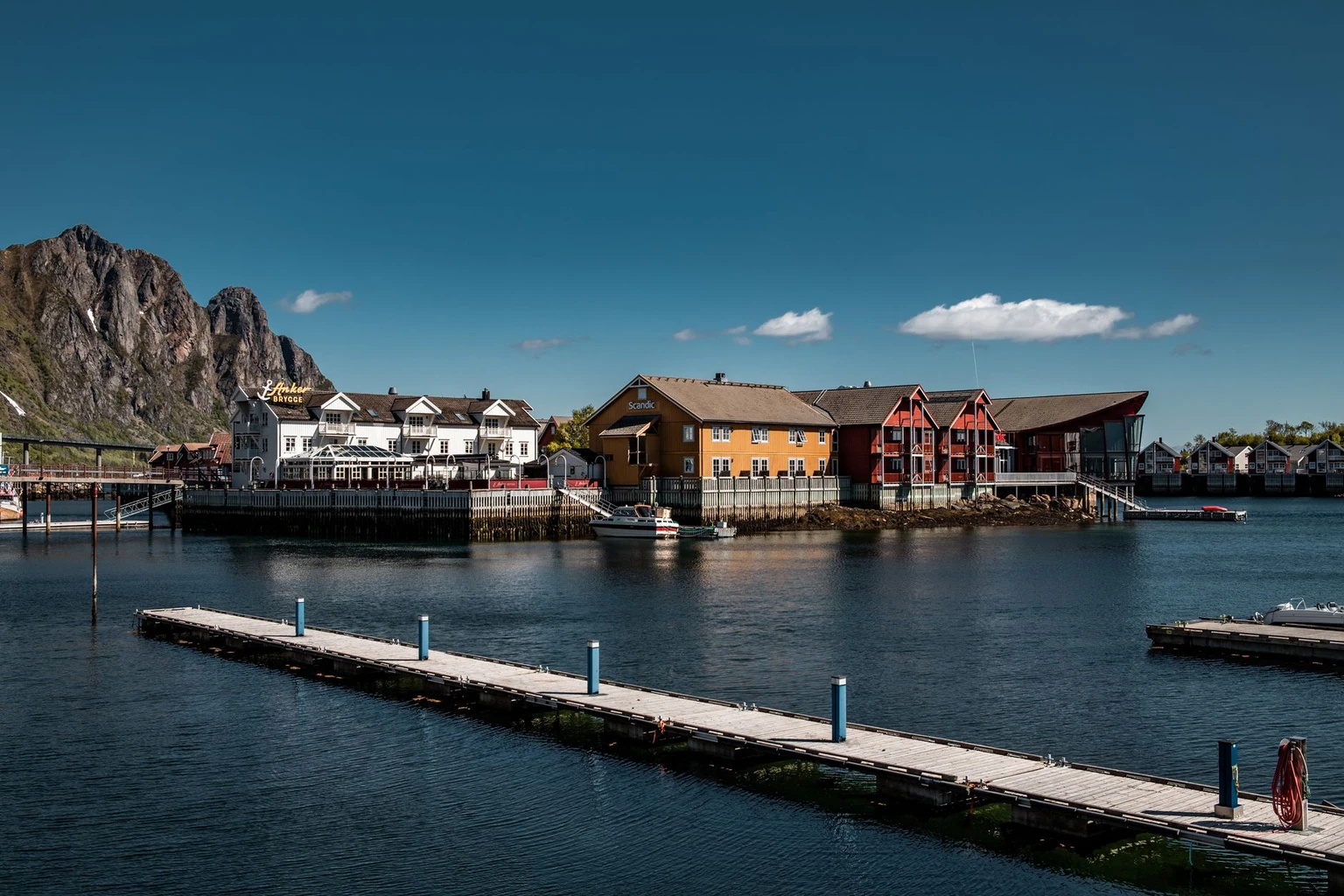 Svolvær harbor in summer with a jetty, old wooden buildings and mountains behind, Lofoten.