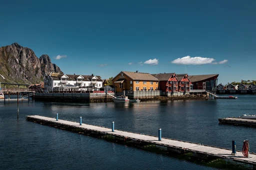Svolvær harbor in summer with a jetty, old wooden buildings and mountains behind, Lofoten.