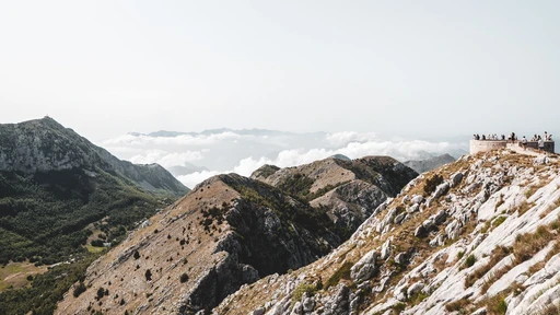 A viewing platform on a Lovcen ridge, with people looking out over the mountains and a sea of cloud below.