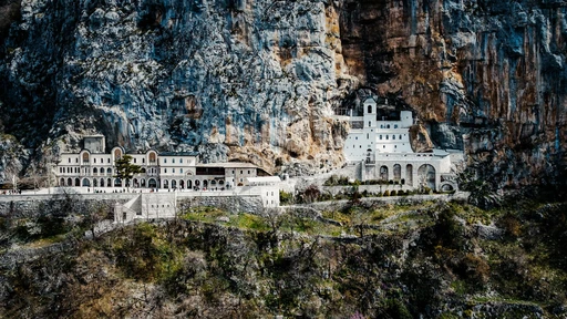 Ostrog Monastery's upper and lower buildings against the grey cliff of Ostroska Greda.