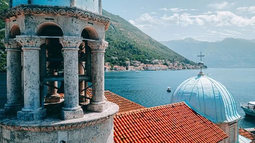 View from the bell tower of the church on Our Lady of the Rocks, over its dome and red roofs to the Bay of Kotor and Perast.