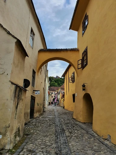 A cobbled alley with arches in Sighișoara's old town.