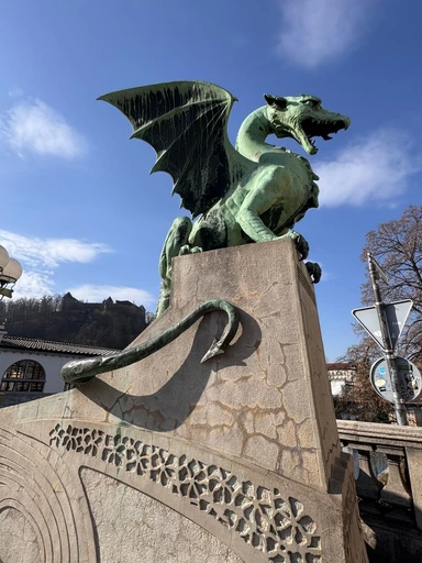The iconic dragon statue on Dragon Bridge, Ljubljana against a clear sky.