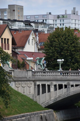 View of Dragon Bridge with iconic statues in Ljubljana, Slovenia under cloudy sky.