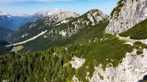 Aerial view of a winding mountain road with hairpin bends climbing through the Julian Alps, Slovenia.