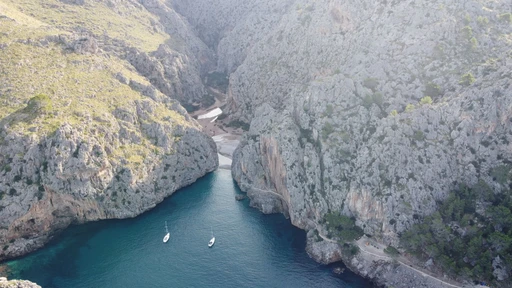 Aerial view of the Sa Calobra cove, its cliffs and blue water, with two boats at anchor.