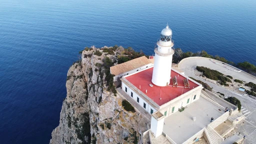 Aerial view of the Cap de Formentor lighthouse and its red roof on the edge of the cliff.