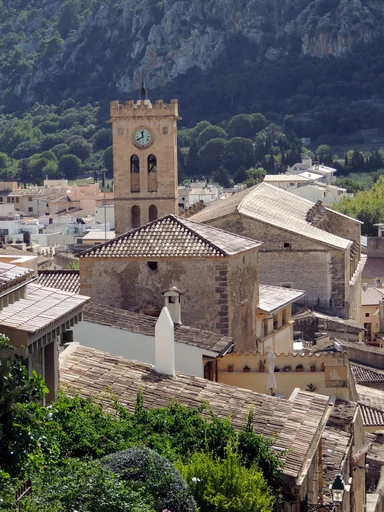 Pollença's old town seen from above, with its clock tower and the mountain behind.