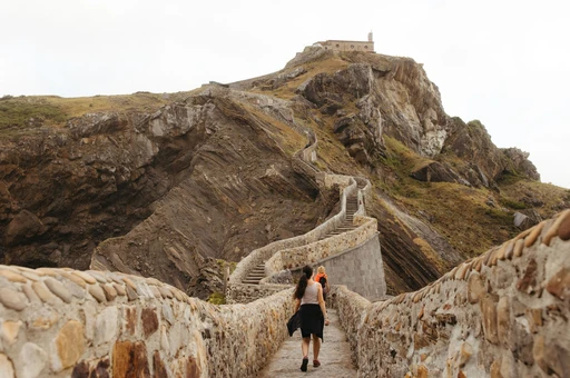 A woman walks up the winding footpath to the iconic Gaztelugatxe islet in the Basque Country, Spain.