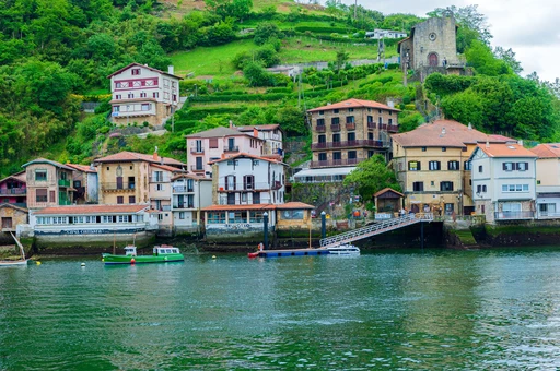 Charming view of a coastal town in Pasaia, Spain with docked boats and hillside buildings.