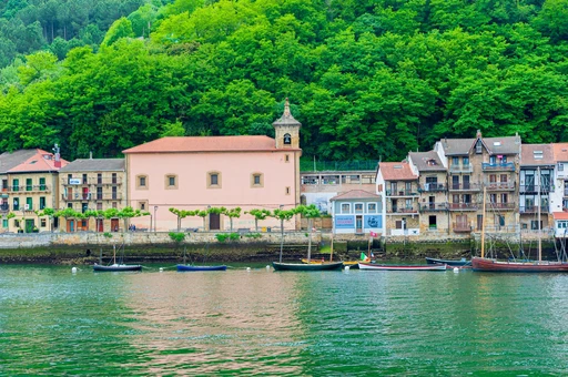 Charming village along a tranquil Spanish waterfront with boats and historic architecture.